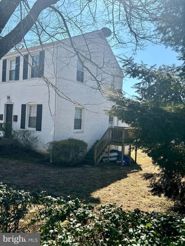 view of side of home featuring brick siding and stairway