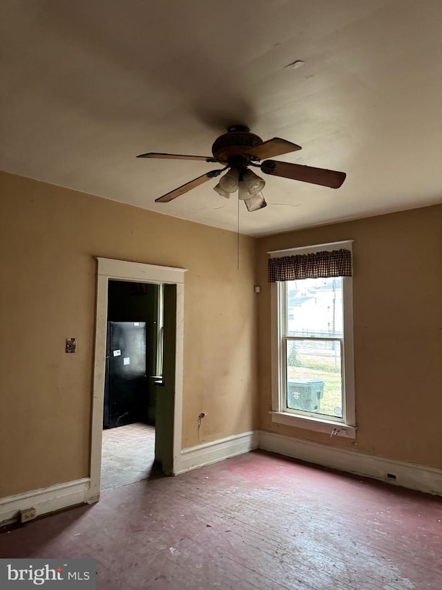 empty room featuring ceiling fan and baseboards