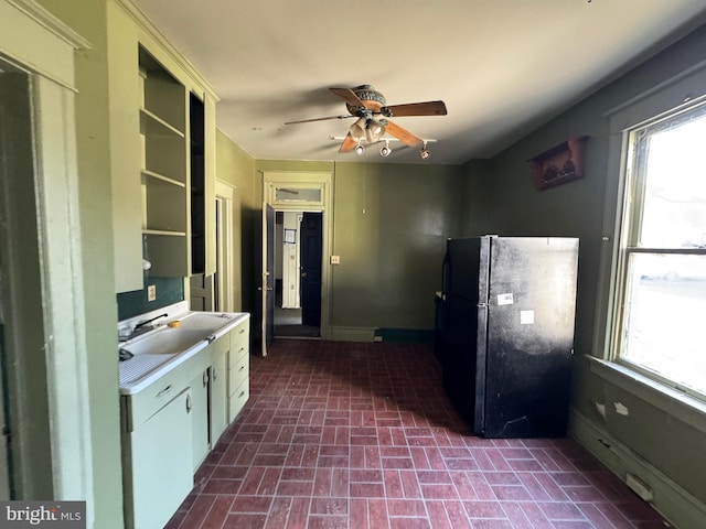 kitchen with brick floor, a ceiling fan, light countertops, freestanding refrigerator, and open shelves