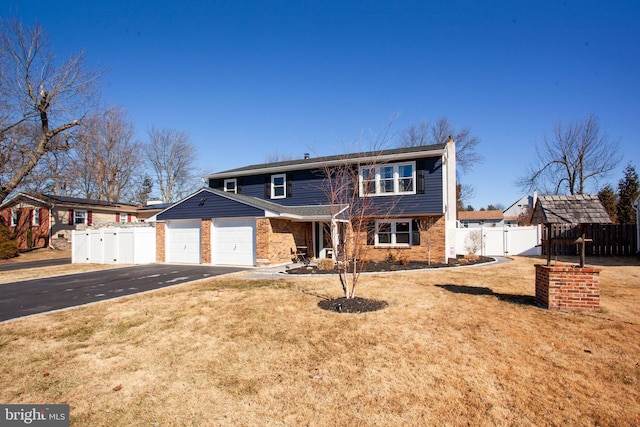 view of front facade with aphalt driveway, an attached garage, a gate, fence, and a front lawn