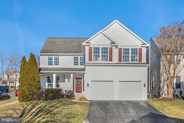 traditional-style home featuring an attached garage, driveway, roof with shingles, and a front yard