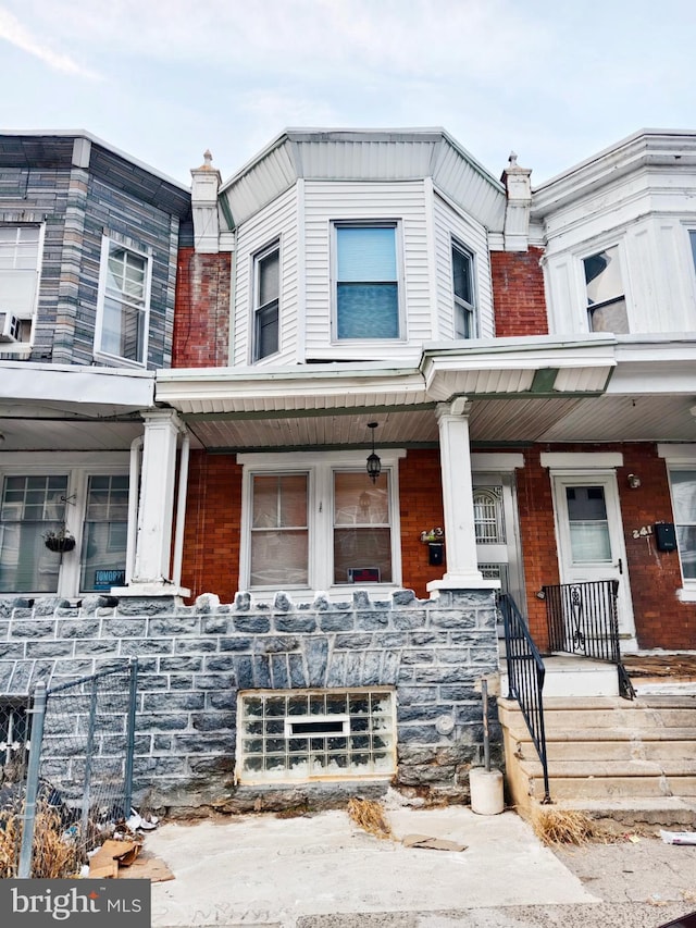 multi unit property featuring covered porch and brick siding