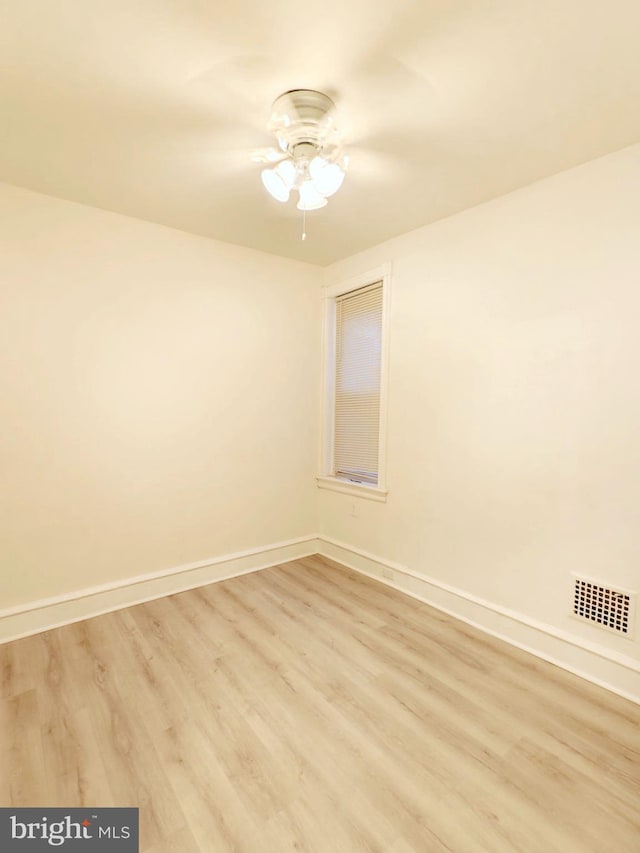 spare room with light wood-style floors, visible vents, and baseboards
