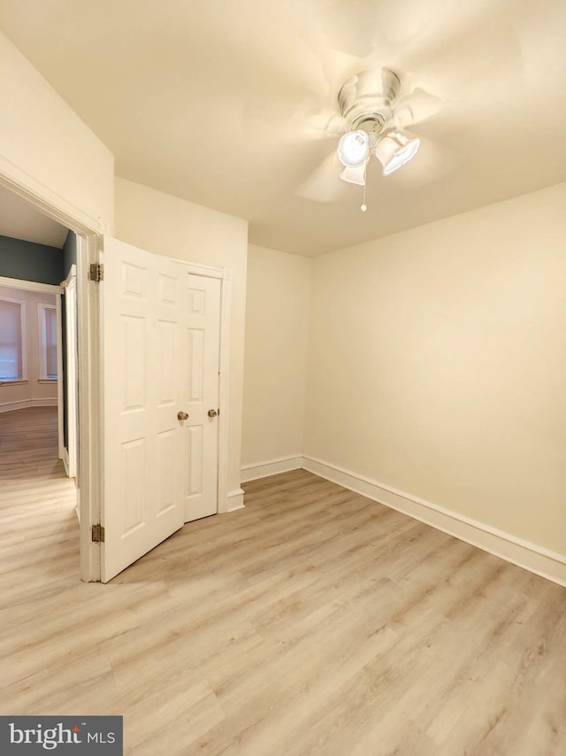 unfurnished bedroom with light wood-style flooring, baseboards, and a ceiling fan