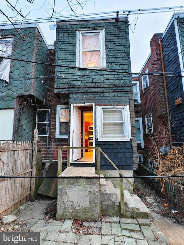 view of front of house with fence, mansard roof, and brick siding