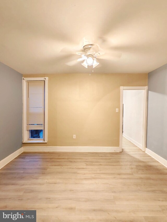 empty room with ceiling fan, light wood-style flooring, and baseboards