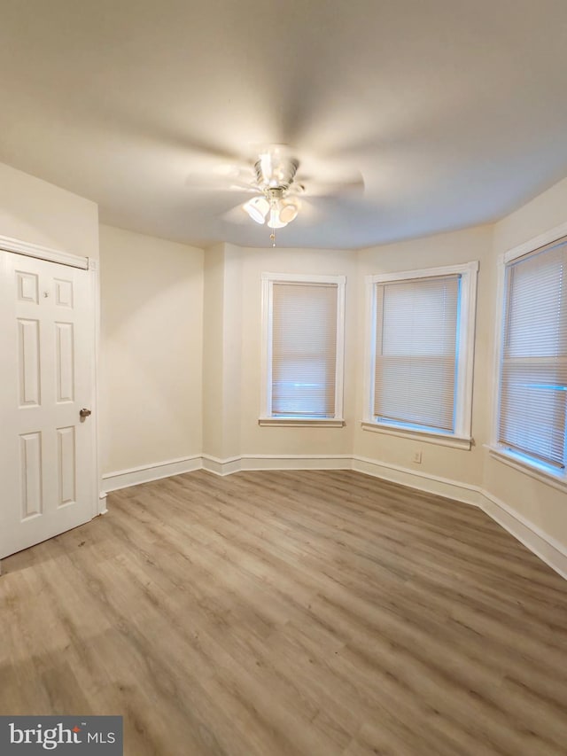 empty room featuring ceiling fan, baseboards, and wood finished floors