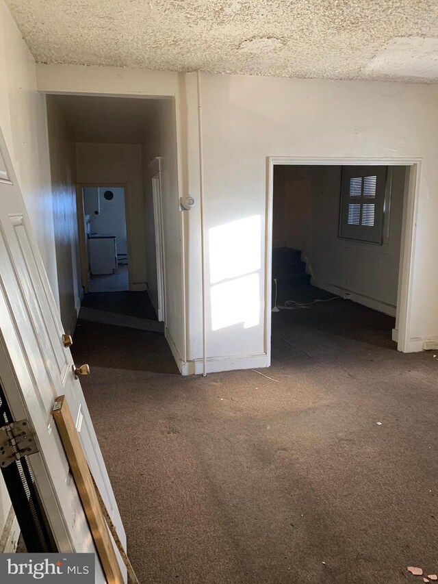 hall with a textured ceiling and carpet flooring