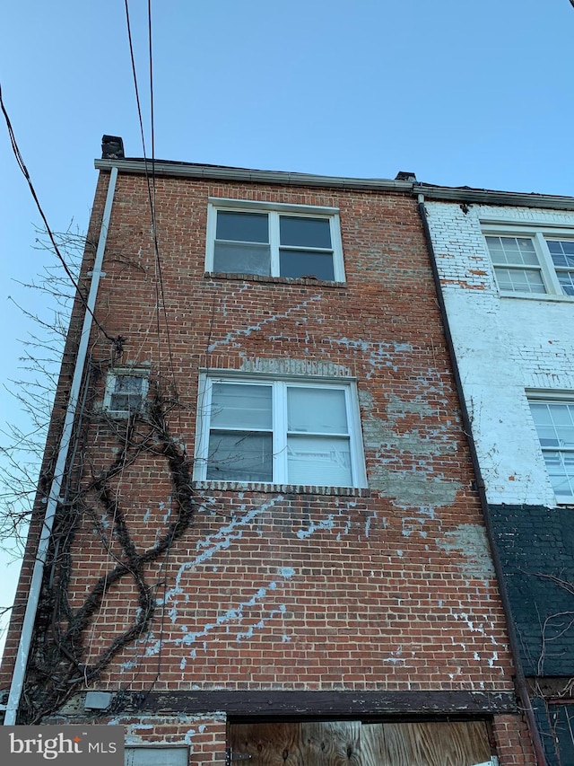 view of side of home featuring brick siding and a garage