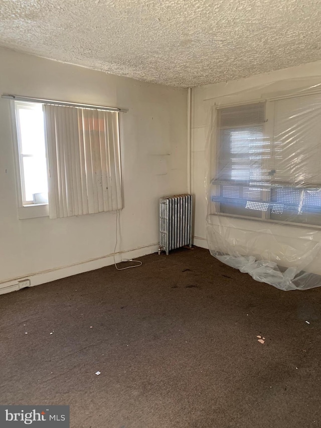 unfurnished room featuring radiator, carpet, and a textured ceiling