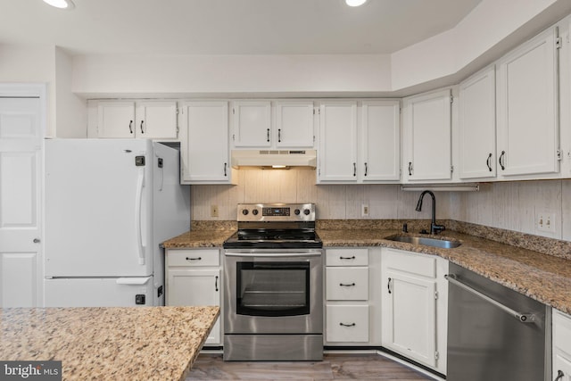 kitchen with appliances with stainless steel finishes, dark wood-type flooring, white cabinetry, a sink, and under cabinet range hood