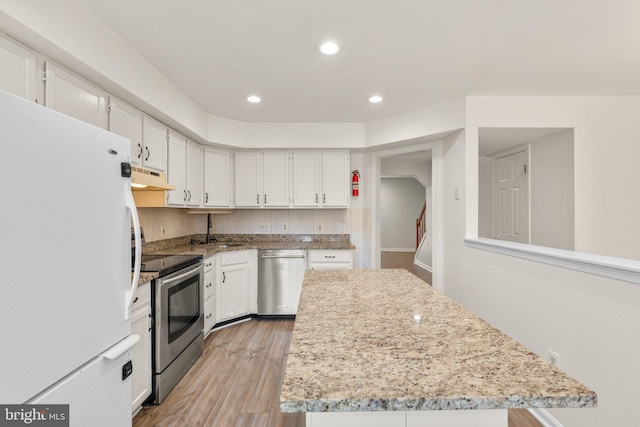 kitchen featuring light wood finished floors, a center island, stainless steel appliances, under cabinet range hood, and white cabinetry