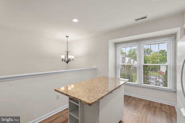 kitchen with an inviting chandelier, baseboards, visible vents, and wood finished floors