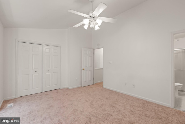 unfurnished bedroom featuring carpet, a closet, connected bathroom, vaulted ceiling, and baseboards