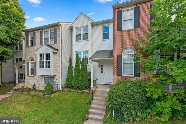 townhome / multi-family property with brick siding and a front yard