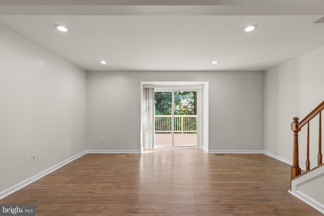 empty room featuring recessed lighting, stairway, baseboards, and wood finished floors