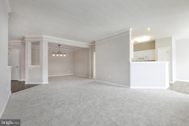 unfurnished living room featuring carpet floors, baseboards, a chandelier, and crown molding