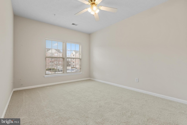 spare room featuring carpet floors, visible vents, baseboards, and a ceiling fan