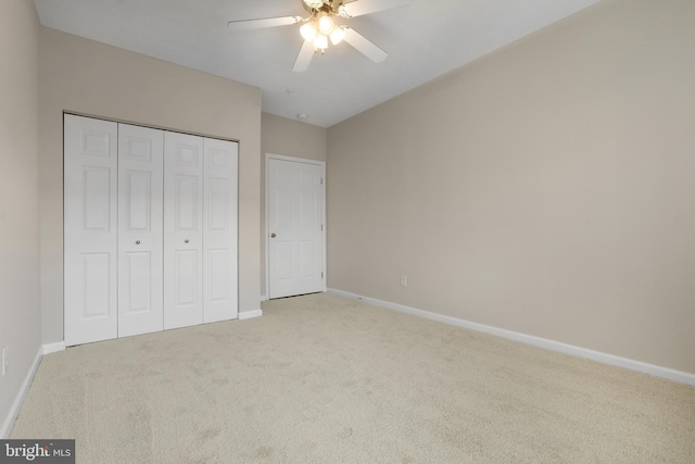 unfurnished bedroom with a closet, light carpet, ceiling fan, and baseboards