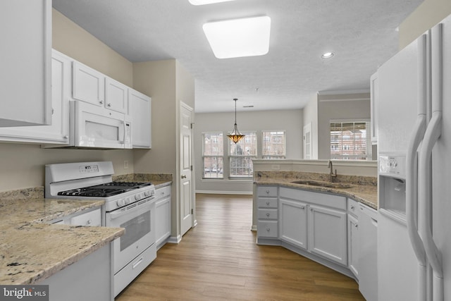 kitchen with decorative light fixtures, white cabinetry, a sink, light wood-type flooring, and white appliances