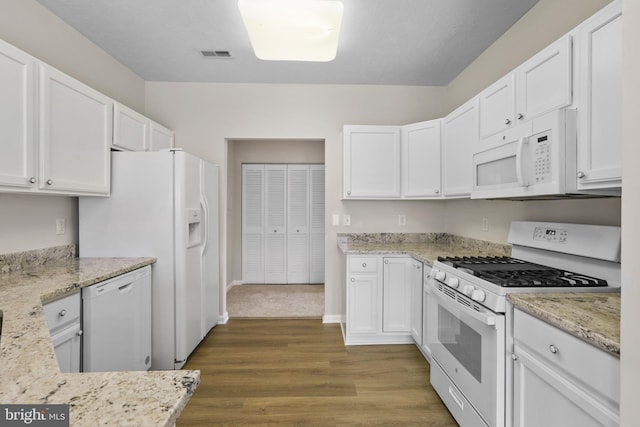 kitchen with white appliances, white cabinets, visible vents, and dark wood-style flooring