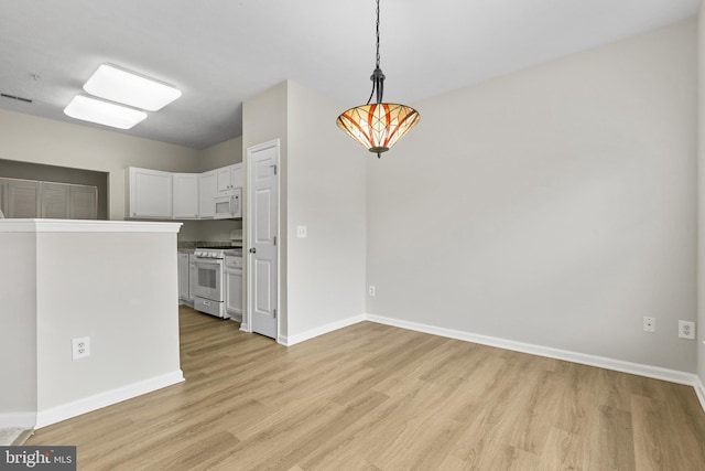 unfurnished dining area featuring light wood-type flooring and baseboards