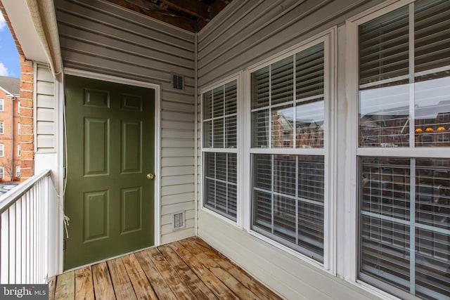 view of exterior entry featuring brick siding and a balcony