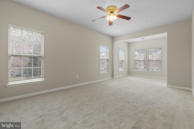 empty room featuring light colored carpet, ceiling fan, and baseboards