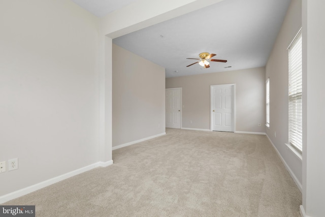 empty room with a ceiling fan, light carpet, and baseboards