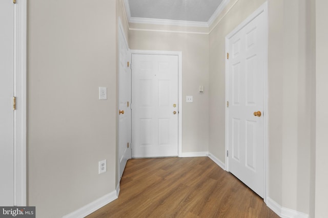 entryway featuring crown molding, wood finished floors, and baseboards