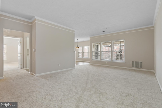 spare room featuring ornamental molding, light colored carpet, visible vents, and baseboards