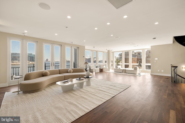 living room with french doors, a city view, recessed lighting, visible vents, and wood finished floors