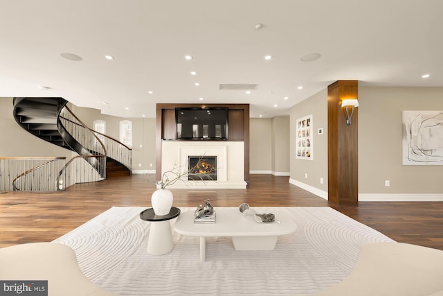 living room with recessed lighting, wood finished floors, a lit fireplace, baseboards, and stairs