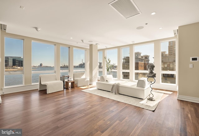 sunroom featuring a water view, visible vents, and a city view