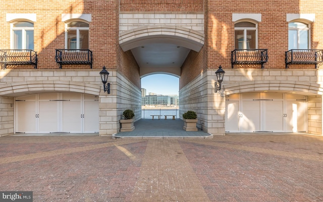 entrance to property with a garage, brick siding, and a balcony