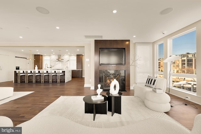 living room with recessed lighting, a large fireplace, dark wood-type flooring, visible vents, and baseboards