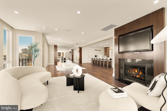 living area with a fireplace, visible vents, wood finished floors, and recessed lighting