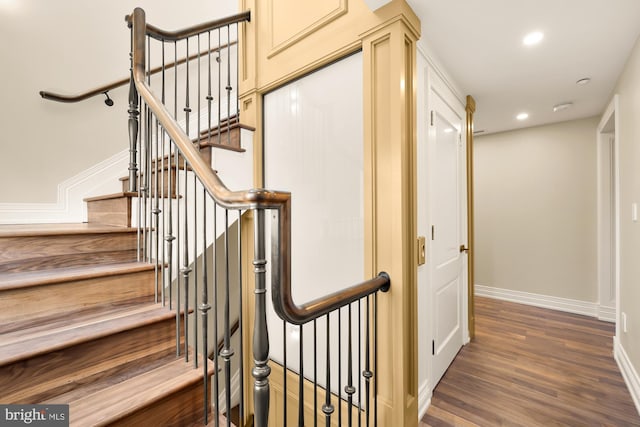 staircase with baseboards, wood finished floors, and recessed lighting