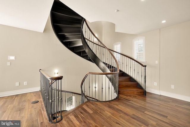 stairway with baseboards, wood finished floors, and recessed lighting