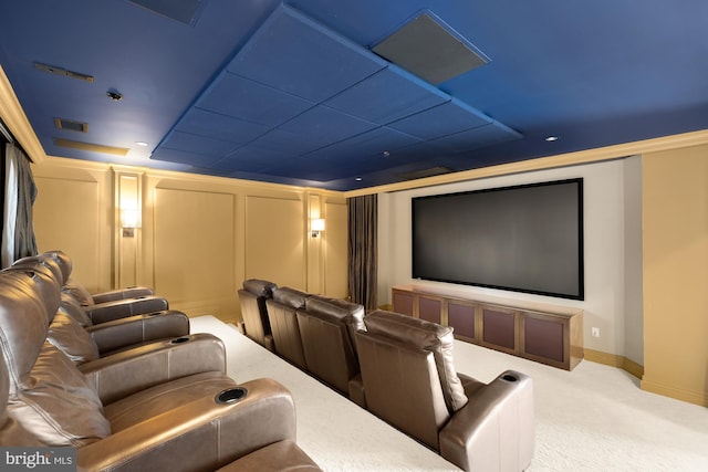 cinema room with light colored carpet, a decorative wall, and visible vents