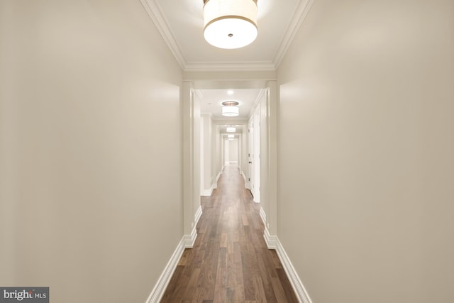 corridor with ornamental molding, dark wood-type flooring, and baseboards