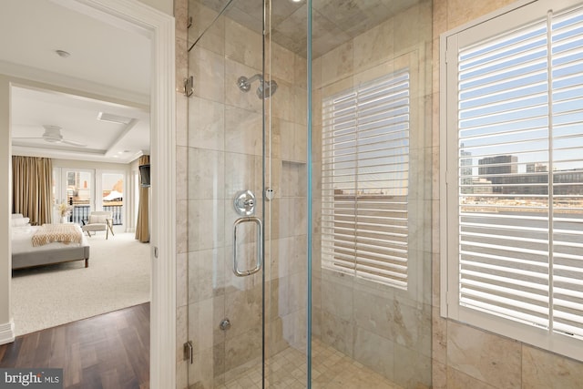 ensuite bathroom featuring a stall shower, a ceiling fan, ensuite bath, wood finished floors, and a wealth of natural light