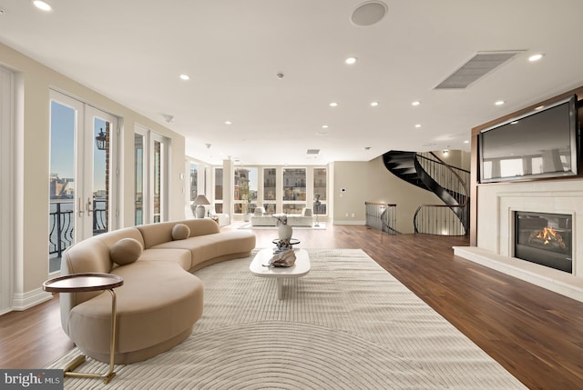 living room featuring french doors, recessed lighting, a glass covered fireplace, wood finished floors, and baseboards