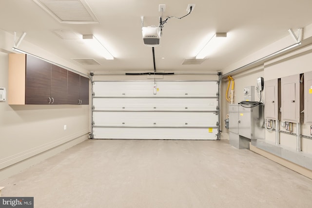 garage featuring visible vents, electric panel, baseboards, and a garage door opener