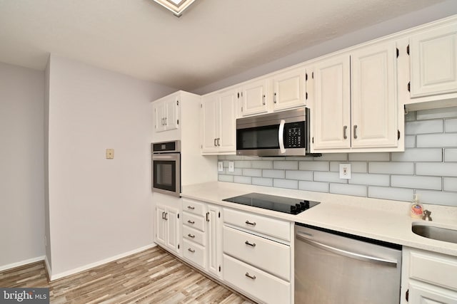 kitchen featuring appliances with stainless steel finishes, white cabinets, and light countertops