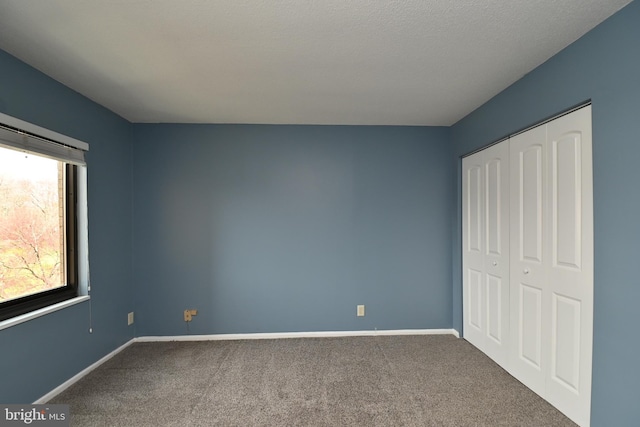 unfurnished bedroom with carpet, a closet, and baseboards