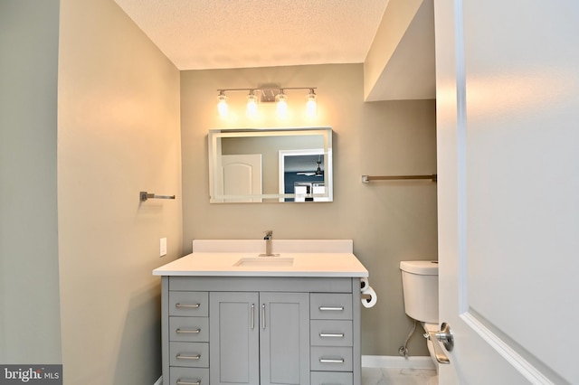 bathroom featuring a textured ceiling, marble finish floor, vanity, and baseboards