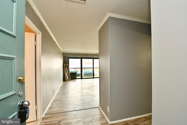 corridor with baseboards, wood finished floors, and crown molding