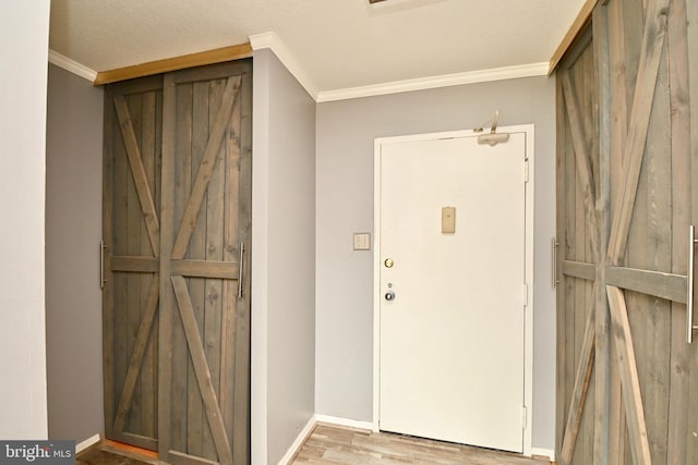 foyer featuring light wood-style flooring, ornamental molding, and baseboards