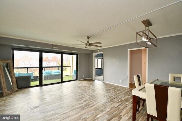 interior space featuring baseboards, visible vents, crown molding, and wood finished floors